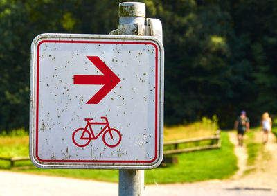 Sign with a red arrow for the direction of the cycle path, soiled by fly droppings