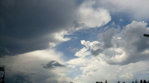 Low angle view of sunlight streaming through clouds