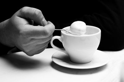 Cropped image of person holding spoon by coffee cup