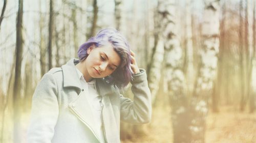 Young woman with dyed hair standing in forest