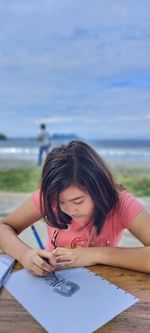 Portrait of young woman standing against sky