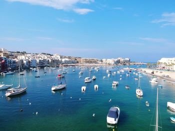 Sailboats moored in sea against blue sky