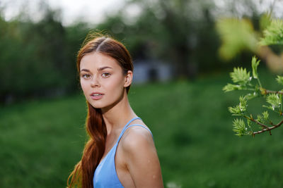 Portrait of smiling young woman standing against plants