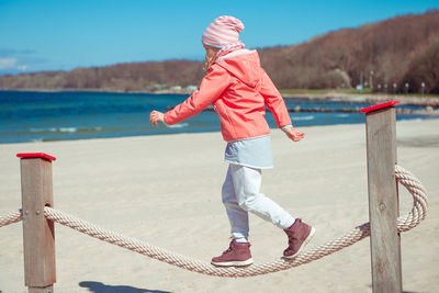 Side view of girl walking on rope at beach