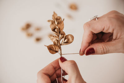 High angle of anonymous female artisan creating decorative flowers and wrapping twig with thread while working in workshop