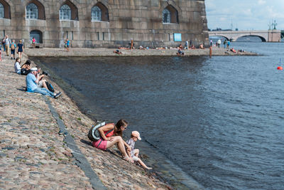 High angle view of woman with son sitting on groyne by river