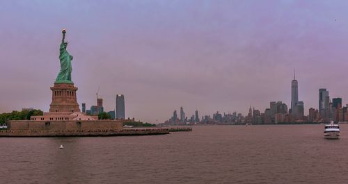 Statue, buildings and city against sky