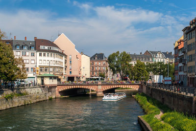 Bridge over river by buildings against sky in city