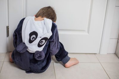 Rear view of boy sitting on floor at home