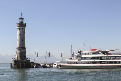 Lighthouse by sea against clear sky