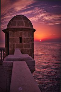 Built structure in sea at sunset