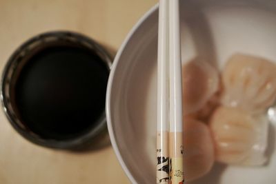 Directly above view of chinese dumplings in bowl with chopsticks and sauce on table