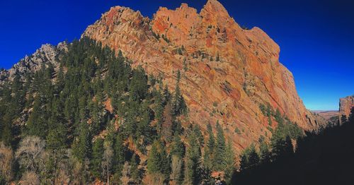 Low angle view of rocky mountain against blue sky