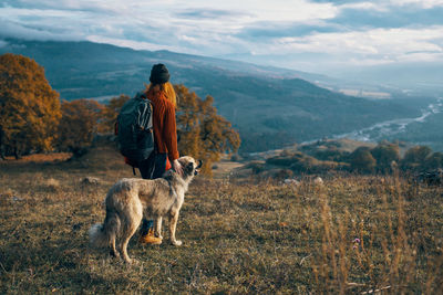 Rear view of man with dog standing on mountain