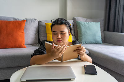 Woman reading diary while sitting at home