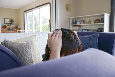 Midsection of woman resting on sofa at home