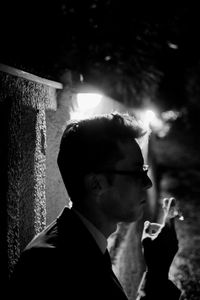 Portrait of young man smoking cigarette at night