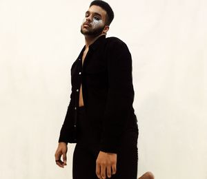 Portrait of young man with face paint while standing against white background