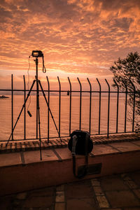 Street light by sea against sky during sunset