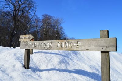 Text on snow covered road against sky