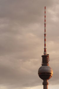 Low angle view of fernsehturm against cloudy sky during sunset