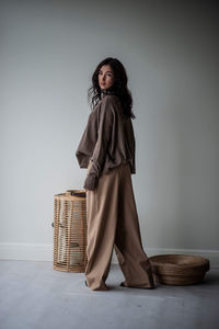 Young woman standing against wall at home