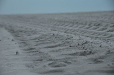 Surface level of sand on beach against clear sky