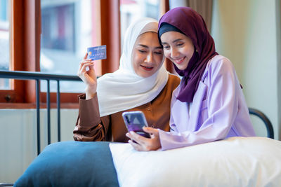 Young woman using mobile phone while sitting on sofa at home