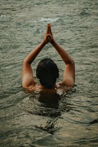 A man is seen from behind who is half submerged in the water