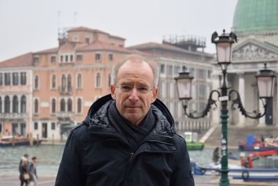 Portrait of smiling man standing in city against sky