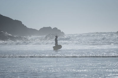 Silhouette man on sea against clear sky
