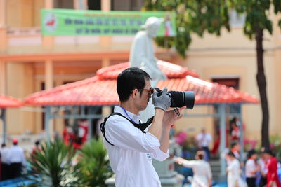 Side view of man photographing in city