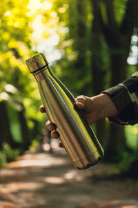 Close-up of unrecognizable female hand holding water bottle. reusable steel thermo water bottle in