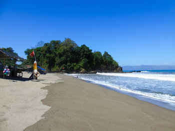 Scenic view of beach against clear blue sky