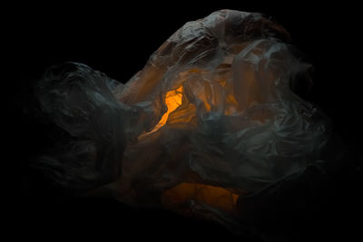 Close-up of burning candle against black background