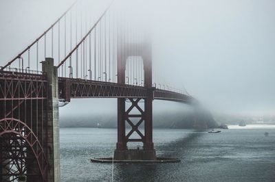 Golden gate bridge over sea against sky in foggy weather