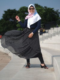 Portrait of smiling woman wearing hijab standing on staircase