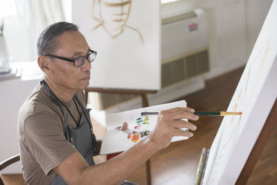 Man painting on canvas at home