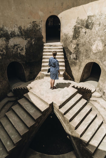 REAR VIEW OF WOMAN STANDING ON STAIRCASE