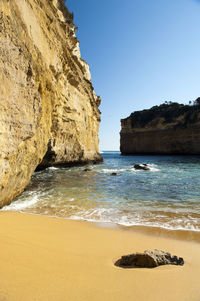 Rock formation on beach against clear sky