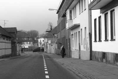 Street amidst houses against clear sky