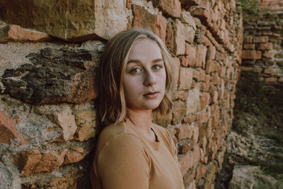 Portrait of woman leaning on brick wall