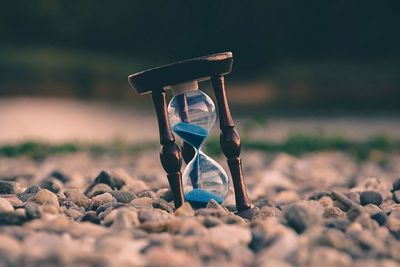 Close-up of hourglass on pebbles