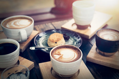 Breakfast with coffee and bread on wooden table under sunlight, vintage color tone, meeting concept.