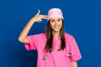 Portrait of smiling young woman standing against blue sky