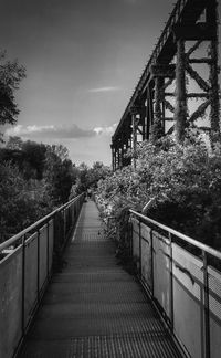 Footbridge over footpath against sky
