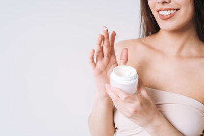 Midsection of woman holding bottle against white background