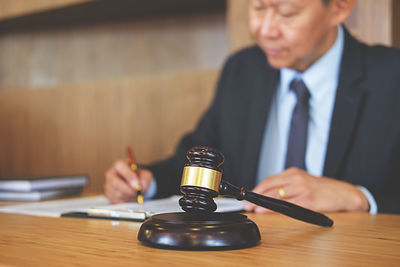 Man writing at desk with gavel