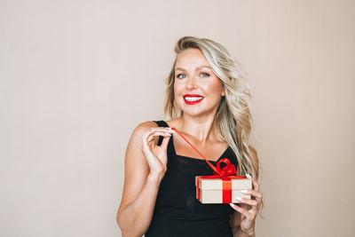 Portrait of young woman using mobile phone against wall