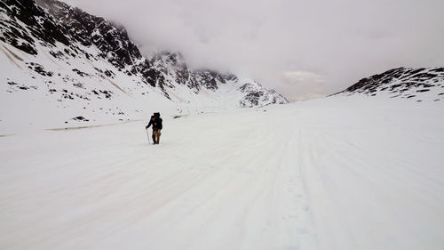 Rear view of person on snowcapped mountain against sky